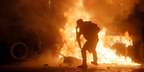 A protester throws a molotov cocktail towards a burning police car. Photo / AP