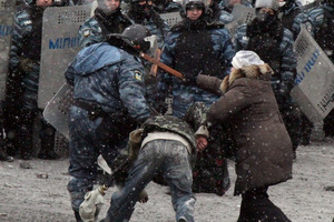 A woman hits a riot police officers with a cross as he pulls a protester during clashes in the center of Kiev. Photo / AFP