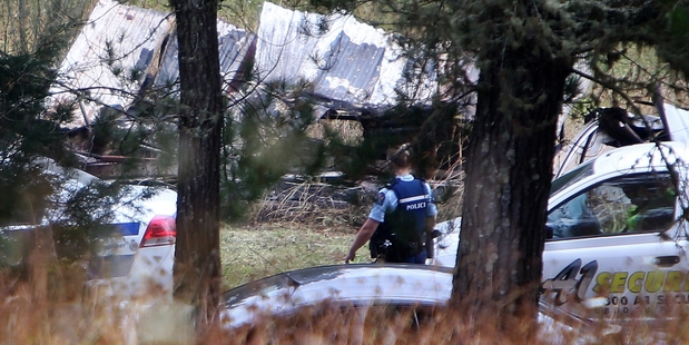WATCHFUL: A police officer was yesterday guarding the remains of a shed destroyed by fire after a suspected P lab exploded. The house (above) by the suspected P lab where two men, severely burned in the blaze, were treated before emergency services arrived. PHOTOS/MICHAEL CUNNINGHAM