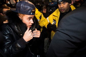 Canadian musician Justin Bieber is swarmed by media and police officers as he turns himself into city police for an expected assault charge in Toronto. Photo/AP