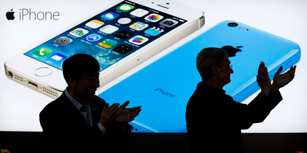 Apple CEO Tim Cook, right, and China Mobile's chairman Xi Guohua are silhouetted against a screen showing iPhone products. Photo / AP