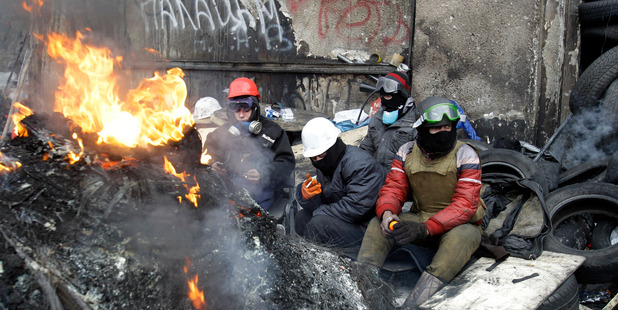Protesters rest behind a barricade in front of riot police in Kiev, Ukraine. Photo / AP