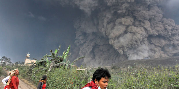 Villagers and a journalist prepare to flee as Mount Sinabung releases pyroclastic flows during an eruption in Namantaran, North Sumatra, Indonesia. Photo / AP