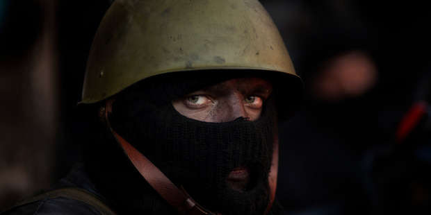 An opposition supporter looks on as he warms himself next to a fire by a barricade near Kiev's Independence Square. Photo / AP