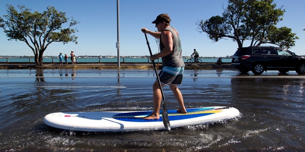 Nick Gant of Kohimarama has a go at paddling on a flooded Tamaki Drive in Auckland. Photo / Richard Robinson