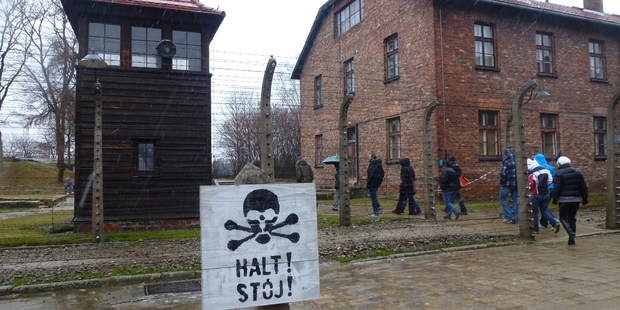 A warning sign at Auschwitz as visitors pass by on a guided tour. Photo / Jared Savage