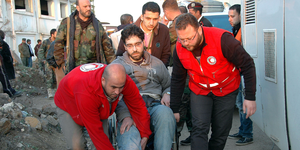 Syrian Arab Red Crescent members in red uniforms help evacuate an injured man. Photo / AP