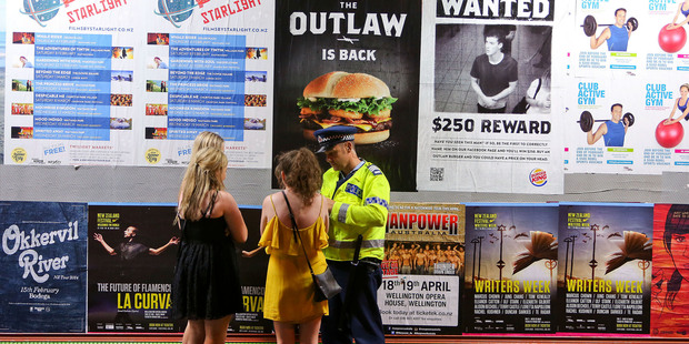 Glen Cooper writes up a ticket for young women caught with alcohol in an alcohol-free zone in Wellington. Photo / Hagen Hopkins