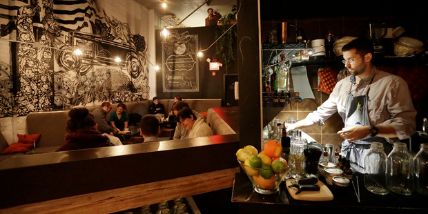 Bartender Joseph Cammarata prepares drinks as patrons sit at tables at the Backbar restaurant and bar in Somerville, Massachusetts. Photo / AP