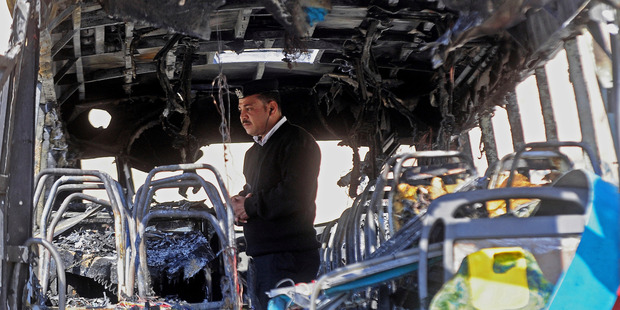 An Egyptian policeman inspects a bus after a deadly explosion ripped through it near the Egyptian border crossing with Israel in Taba, Egypt. Photo / AP