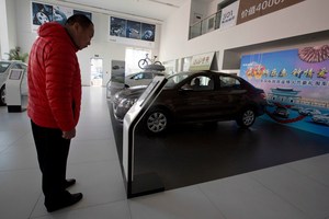 A customer looks at a Peugeot car on display at a Dongfeng and Peugeot joint venture showroom in Beijing.Pictures / AP