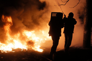 Activists extinguish a tree which caught fire at the burning barricades close to Independence Square. Photo / AP
