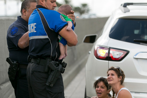 Officer Amauris Bastidas helps rescue a five-month-old baby boy, Sebastian de la Cruz. Photo / AP Photo/The Miami Herald, Al Diaz