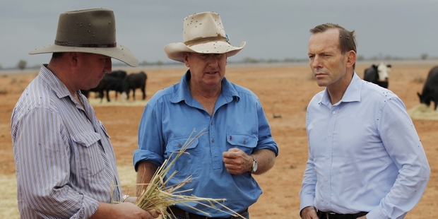 Prime Minister Tony Abbott (right), seen talking to drought-stricken farmers, has fallen in the polls but approval of his Government is up. Photo / Getty Images