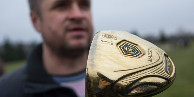 A man holds a golf club with the name of Ukrainian President Viktor Yanukovich on a golf course at the Ukrainian President Yanukovych's countryside residence. Photo / AP