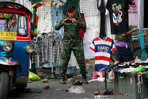 A soldier photographs the scene of an explosion littered with blood and small pairs of shoes at a main protest site in Bangkok, Thailand. Photo / AP