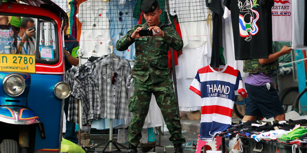 A soldier photographs the scene of an explosion littered with blood and small pairs of shoes at a main protest site in Bangkok, Thailand. Photo / AP
