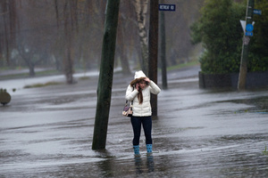 A young woman walks along a flooded Avonside Drive. File photo / Martin Hunter