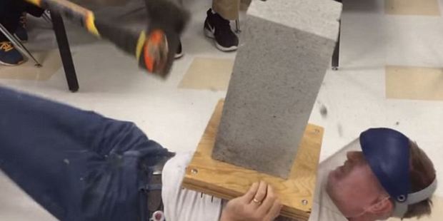 Teacher tries to give lesson by showing effect of an axe on a cinder block, but misjudges swing, bringing tool directly into fellow teacher's groin.