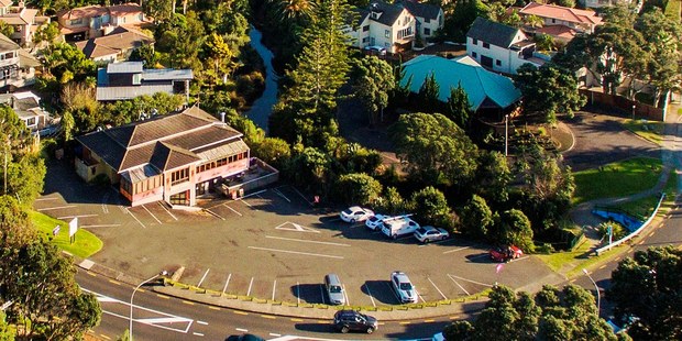 Aerial view of a two level building for sale on a large site at 470 Beach Rd, Murrays Bay.