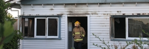 GUTTED: A firefighter steps out the front door of a Rexwood St property, Carterton, gutted in a suspicious early morning blaze. PHOTO/ANDREW BONALLACK