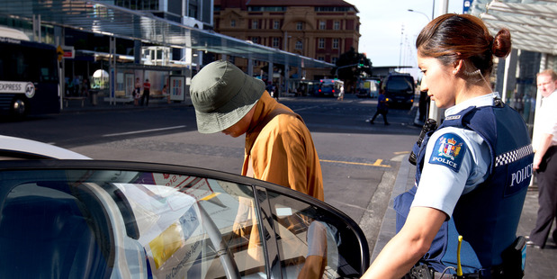 A policewoman removes one of the "monks" from the Auckland CBD. Photo / Dean Purcell