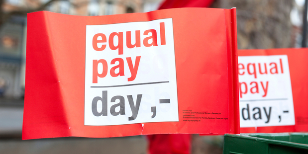 Red flags at an Equal Pay Day rally in Germany. The day illustrates how much longer women have to work in a year to earn the same amount made by a man in the previous 12 months. Image / iStock