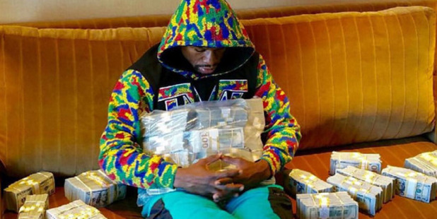 Boxer Floyd Mayweather wraps himself in money. Photo / Instagram