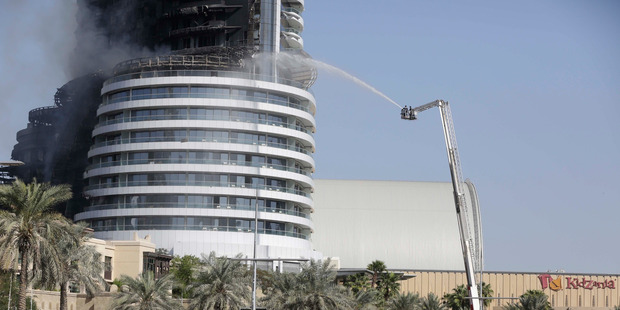 Firefighters spray water on the still burning Address Downtown. Photo / AP