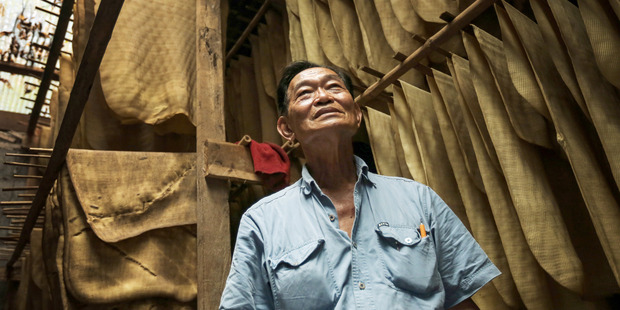 Farmer Winai Chaikunanant stands next to sheets of rubber drying at his rubber farm in Rayong province, Thailand, in October. Photo / Bloomberg