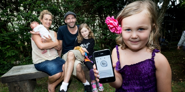 Gabrielle and Simon Hall with 2-week-old Stella, Mia, 8, and Georgia, 4, who shows off the smartphone tracking her glucose levels. Photo / Dean Purcell
