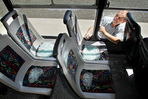 Nimon buses general manager Pete Patterson checks the broken windows of the vandalised bus. Photo / Warren Buckland