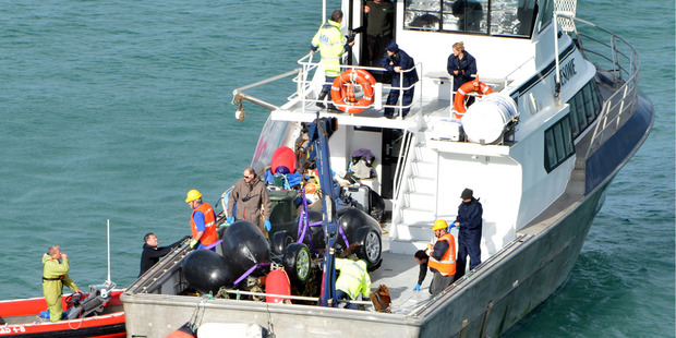 The remains of a Volkswagen Touareg car are lifted onto a boat in Curio Bay on the Catlins Coast.
