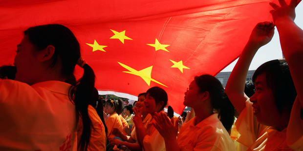 Graduates of Hubei University of Economics in China cheer under the national flag. China has been accused of spying on universities in Australia. Photo / Getty Images