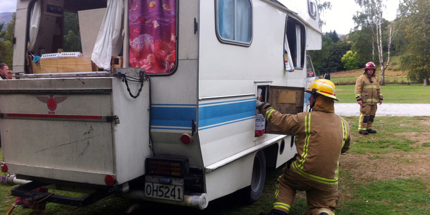 Fire volunteers inspect a damaged camper at Lake Hayes after a gas bottle explosion injured two women. Photo: David Williams/Otago Daily Times