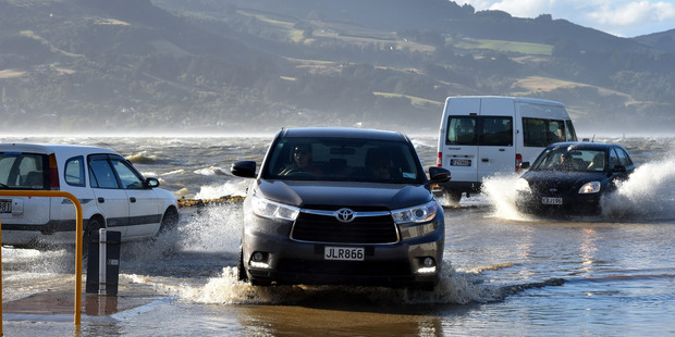 Cars ploughs through sea water that inundated Portobello Rd at Macandrew Bay. Photo / Gregor Richardson, Otago Daily Times
