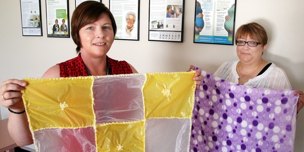 Angela Adam (left) holds a stitched blanket made out of plastic supermarket bags. Lucy Pettit holds a polar fleece blanket. They say wrapping your baby in either has the same effect: Overheating. Photo / Stuart Munro