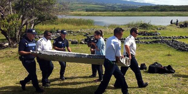 Police carry a piece of debris found in the coastal area of Saint-Andre de la Reunion. Photo / Getty Images