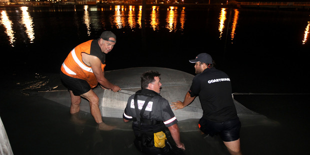 Volunteers from the Napier Coastguard work to bring the upturned boat ashore at Westshore, Napier. Photo / Hawkes Bay Today