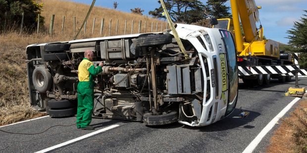 Cranes being used to right a school bus that rolled on it's side with six students aboard. Photo / Mark Mitchell