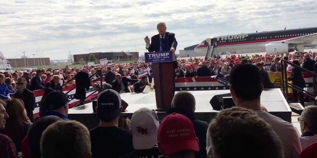 A man who jumped over a security barrier runs behind the dais where Republican presidential candidate Donald Trump is speaking during a campaign stop outside Dayton. Photo / AP