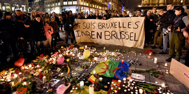 People holding a banner reading 'I am Brussels' behind flowers and candles to mourn for the victims at Place de la Bourse in the centre of Brussels. AP photo / Martin Meissner