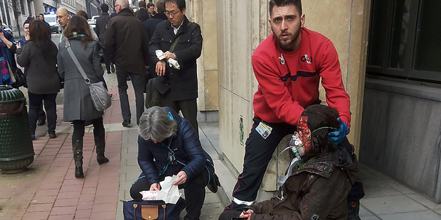 A private security guard helps a wounded women outside the Maalbeek metro station in Brussels. Photo / Getty