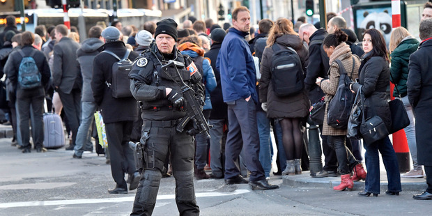 People queue for buses behind a policeman in Brussels. Photo / AP