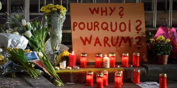 A sign reads 'Why?' in English, French and Flemish behind candles and flowers near the Maelbeek metro station, in Brussels. Photo / AP