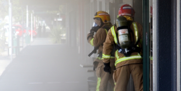 SMOKE OUT, FIREMEN IN: Pungent smoke pouring into Kaitaia's main street as firefighters using breathing apparatus prepare to enter Town and Country Food.