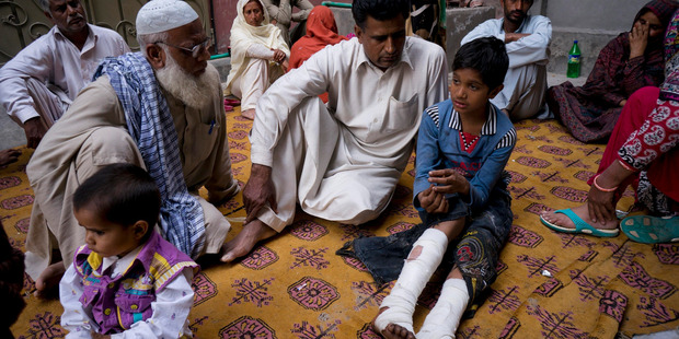 Fahd Ali, 10, right, who was injured in a bombing that killed his parents and sister and wounded two sisters, talks to visitors at in Lahore, Pakistan. Photo / AP