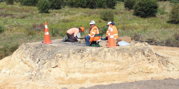 Archaeologists excavate the koiwi as kaitiaki Kawe Nikora (seated) supervises.