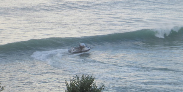 A strong wave threatens to flip the fishing boat over.