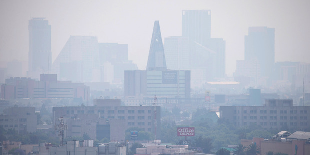 Smog blankets scyscrapers in Mexico City. Increasingly polluted air and water are among the health risks that could be exacerbated by global warming. Photo / AP